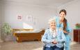 Lächelnde Seniorin im Rollstuhl mit Pflegekraft