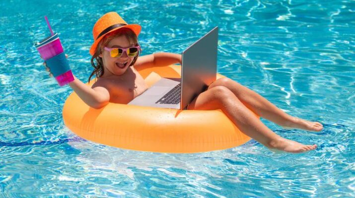 Kleines Mädchen entspannt sich im Pool mit Laptop, Schwimmreifen und einem Getränk.