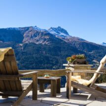 Holzsessel auf der Terrasse einer Berghütte mit Panoramablick auf die wunderschöne Alpenlandschaft im Herbst