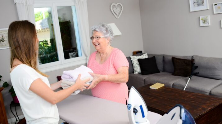 Pflegedienst hilft älteren Frau beim Handtuch falten