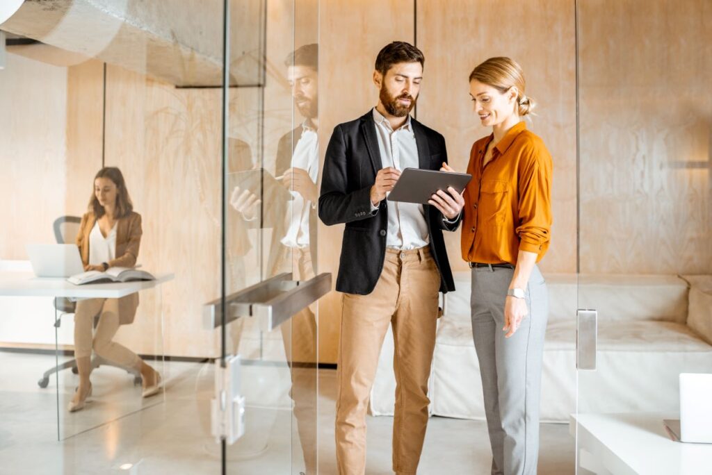 Zwei Geschäftsleute im Gespräch mit Tablet, symbolisierend die Nutzung von ERP-Software Sage für effektive Zusammenarbeit im Büro.