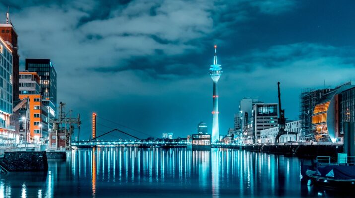 Beleuchtete moderne Architektur in Düsseldorf mit reflektierendem Wasser.