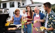 Familie grillt gemeinsam vor dem Haus im Garten