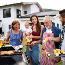 Familie grillt gemeinsam vor dem Haus im Garten