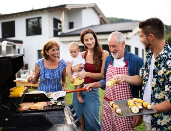 Familie grillt gemeinsam vor dem Haus im Garten