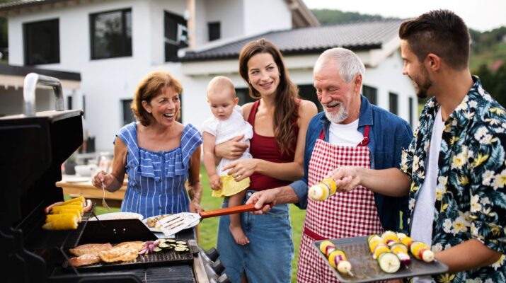 Familie grillt gemeinsam vor dem Haus im Garten