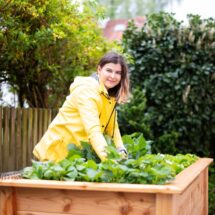 Frau mit gelber Jacke am Hochbeet bei der Arbeit im Gartenbau Mannheim mit regionaler Bepflanzung