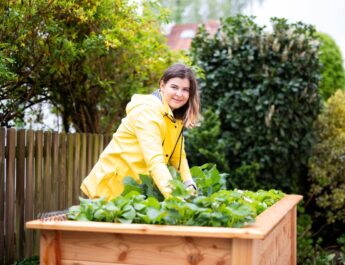 Frau mit gelber Jacke am Hochbeet bei der Arbeit im Gartenbau Mannheim mit regionaler Bepflanzung