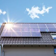 Photovoltaikanlage Krefeld auf einem Schrägdach bei blauem Himmel mit Sonnenreflexion auf den Solarmodulen