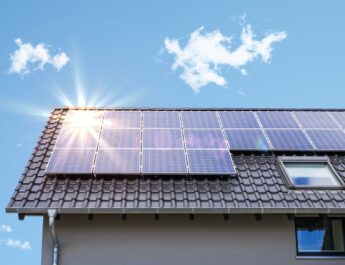 Photovoltaikanlage Krefeld auf einem Schrägdach bei blauem Himmel mit Sonnenreflexion auf den Solarmodulen