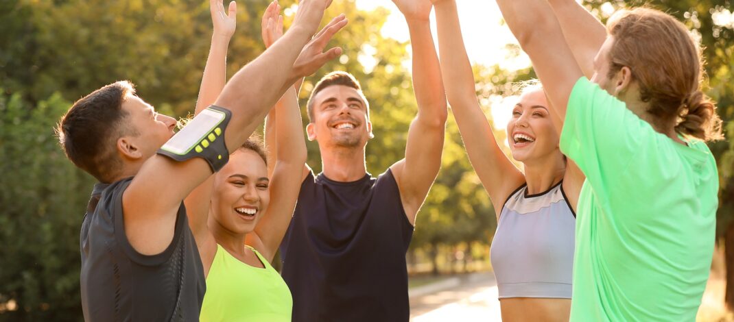 Sportgruppe jubelt nach Training im Park | Sportmediziner Köln