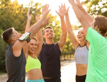 Sportgruppe jubelt nach Training im Park | Sportmediziner Köln