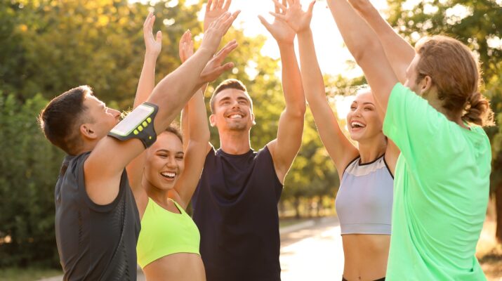 Sportgruppe jubelt nach Training im Park | Sportmediziner Köln