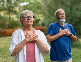 Älteres Paar übt Achtsamkeit und tiefe Atmung im Garten | finnische Sauna